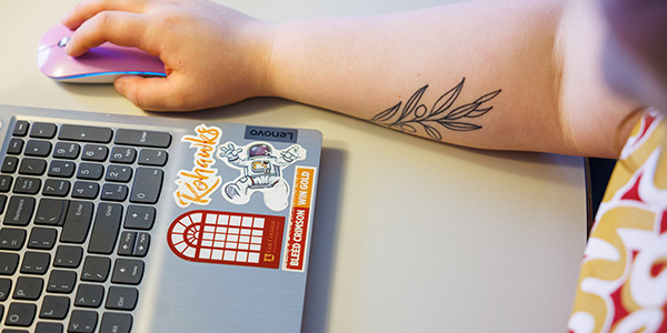 Student using laptop with Coe stickers