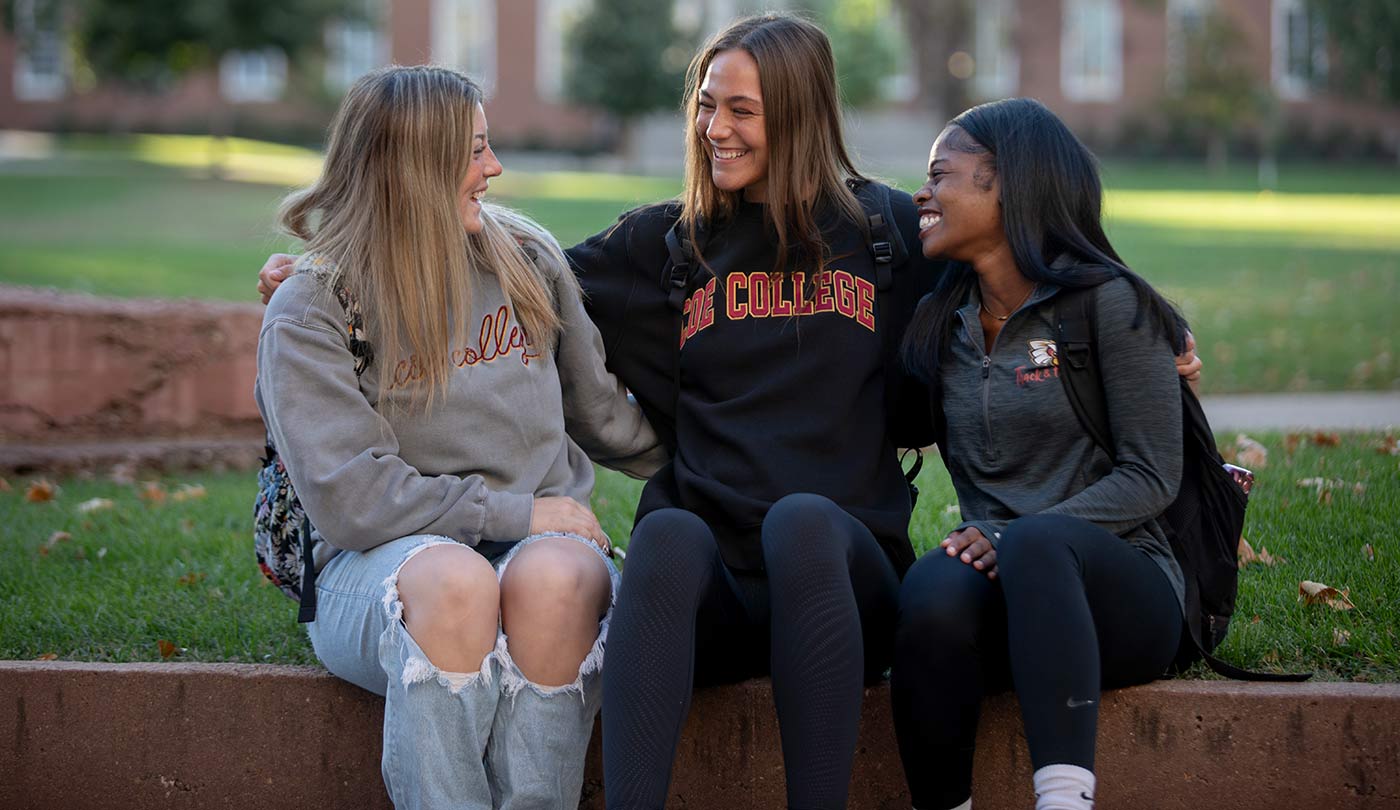 Three female students looking at each other and laughing