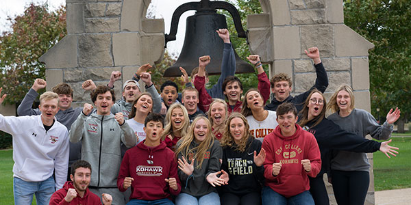 Crowd of Coe students cheering in front of the Victory Bell