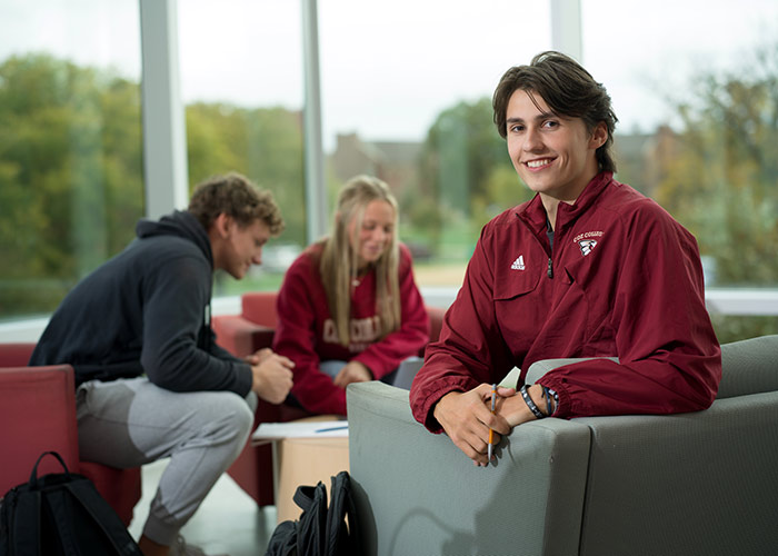 Male student smiling in front of out of focus students
