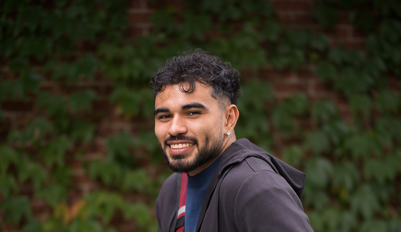 Male student smiling in front of ivy