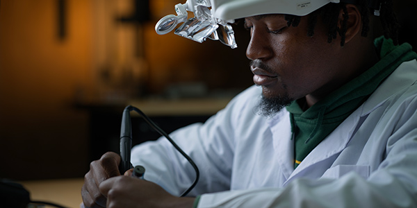 Student wearing lab coat and working on project
