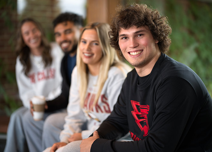 Male Coe student smiling in front of line of Coe students