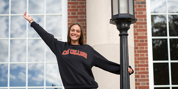 Female Coe student hanging off of light pole
