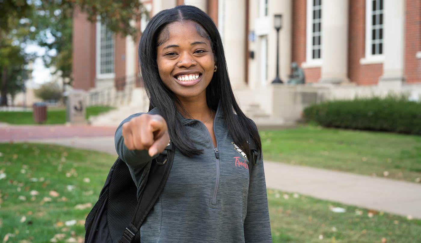 Female Coe student pointing at the camera